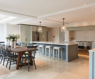 large open plan kitchen diner with long blue kitchen island and stone floor