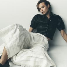Model wearing a black blouse and white layered wide leg pants sold at Anthropologie