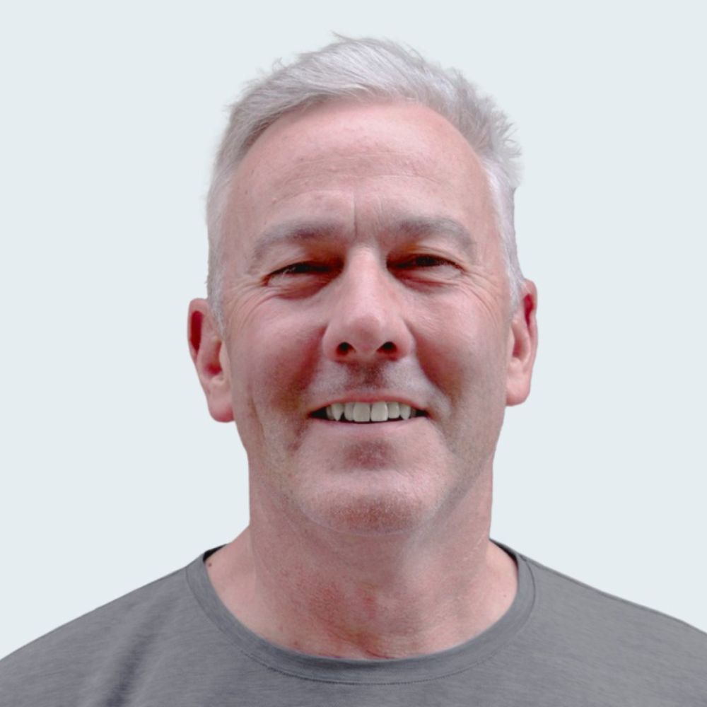 Headshot of a middle aged man smiling at the camera with a white background