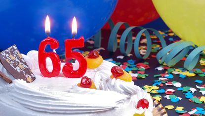 A cake with a candle saying 65.