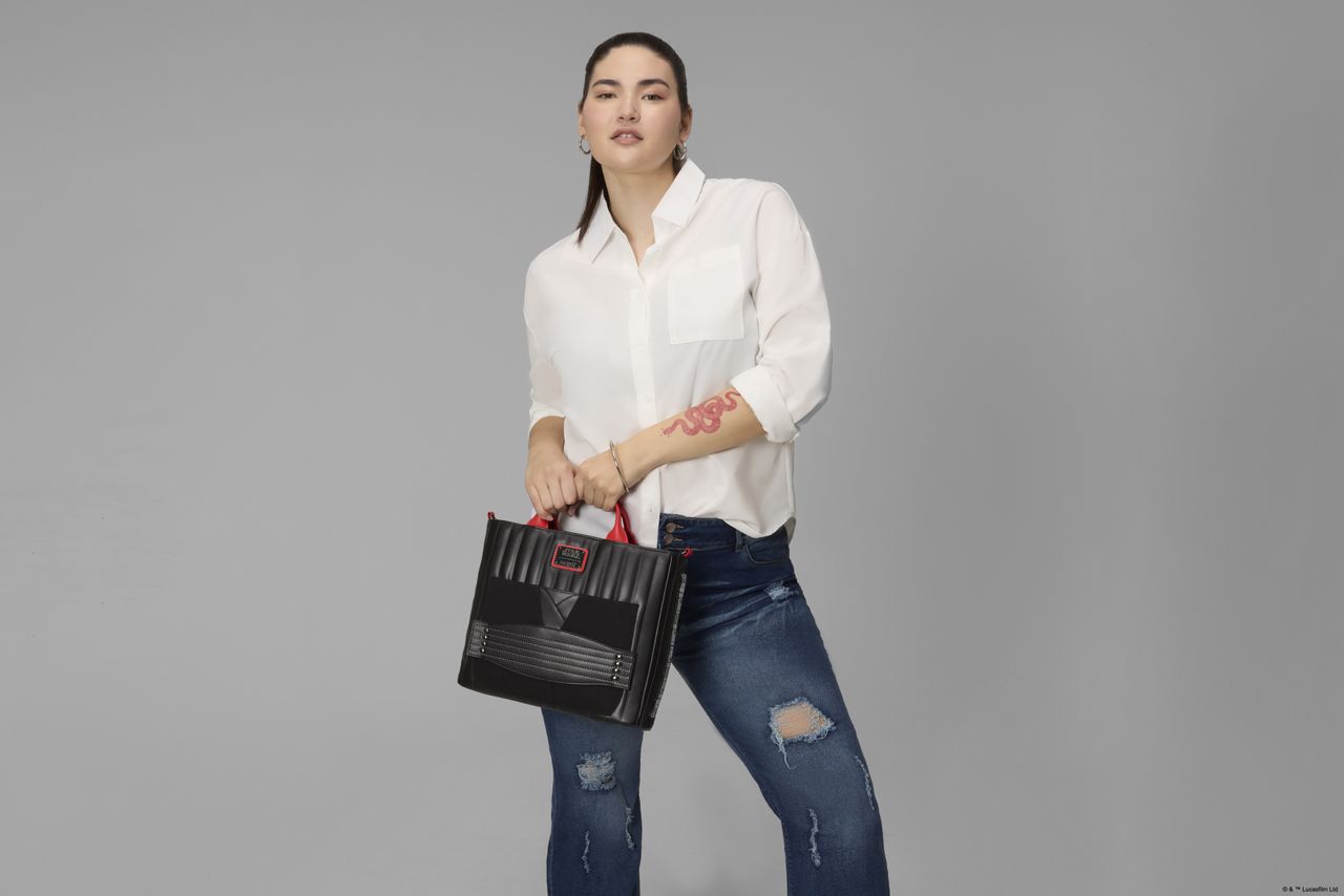 A woman holds the Loungefly Darth Maul bag in a gray environment