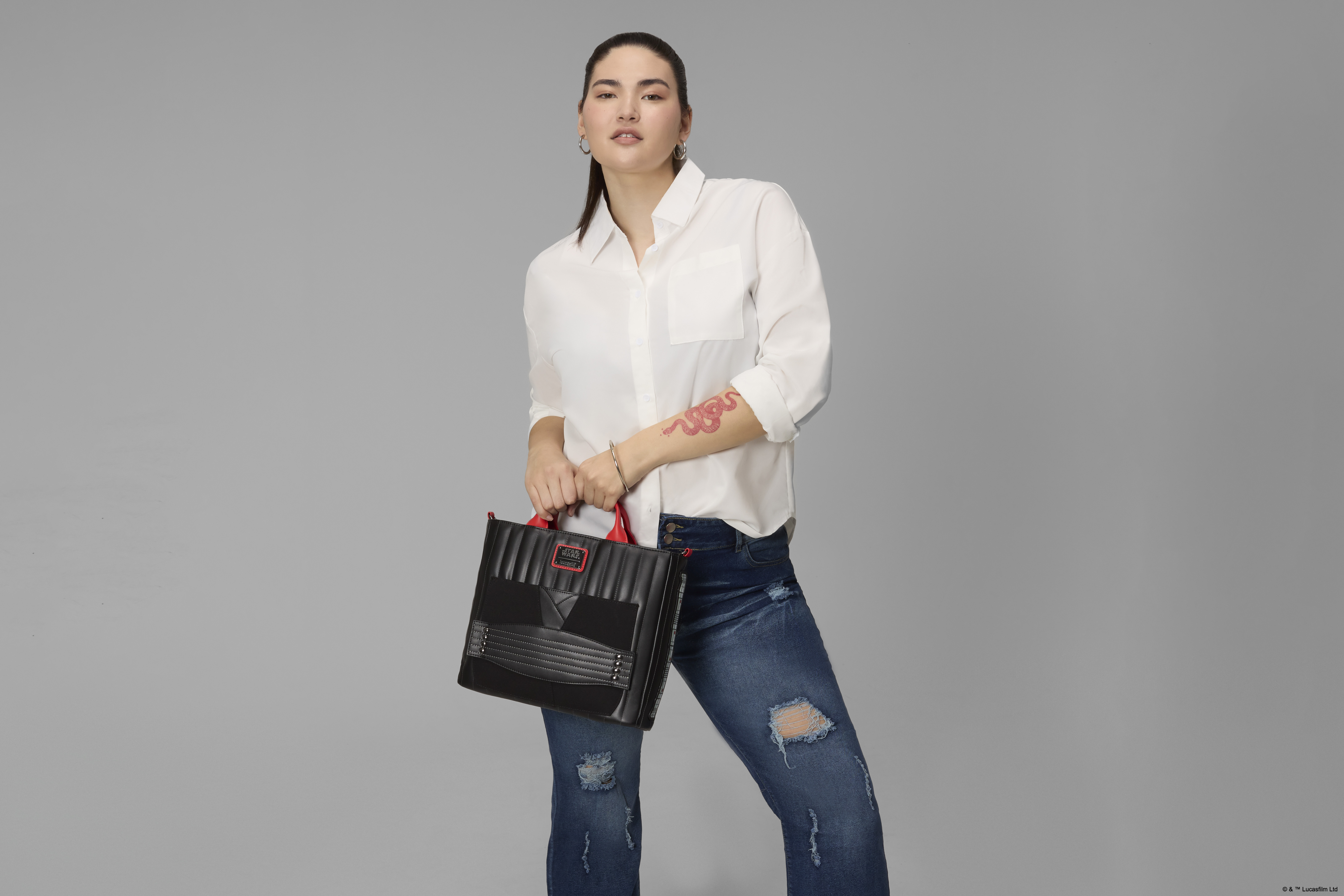 A woman holds the Loungefly Darth Maul bag in a gray environment