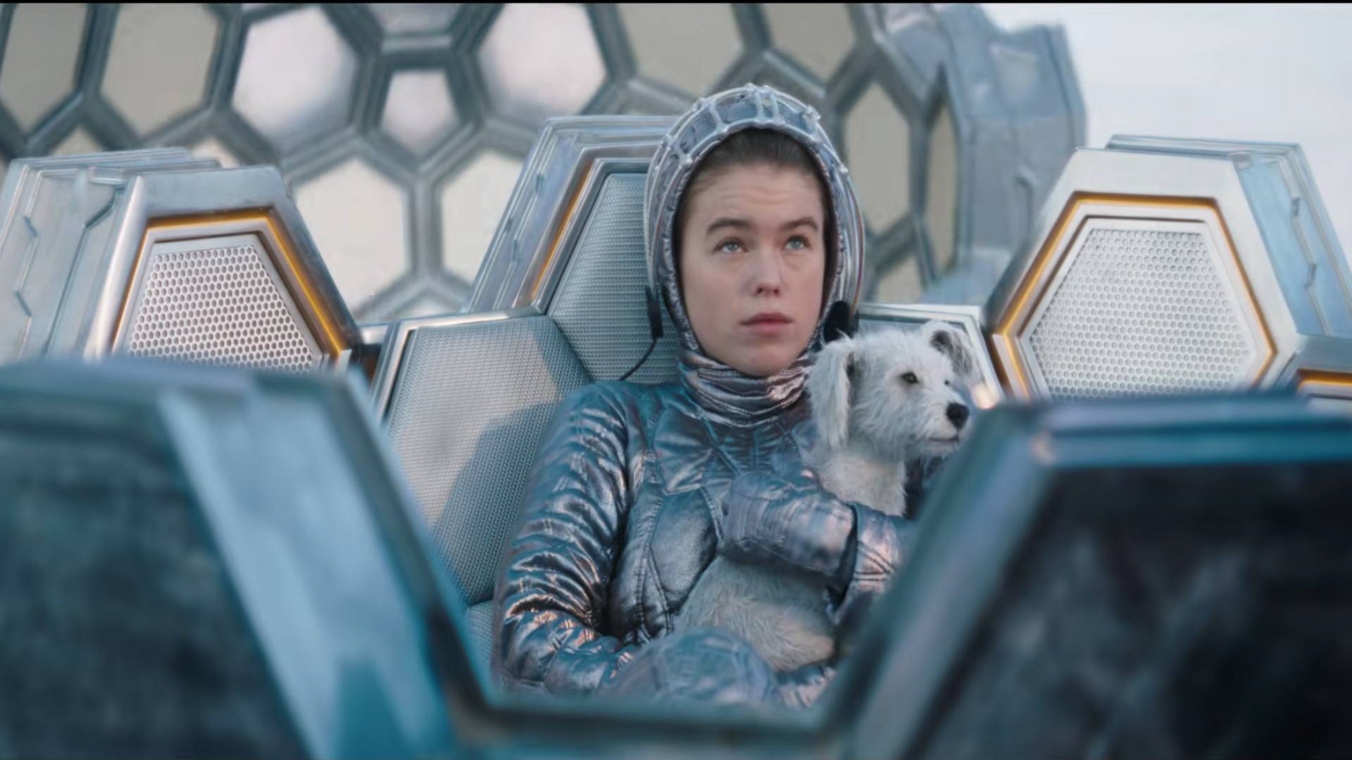 a young girl in a silver sci-fi suit holding a dog