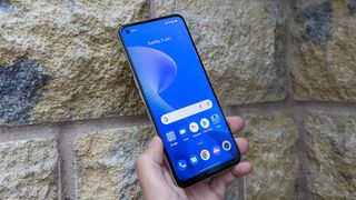 The Realme 9 being held up face forwards against a wall