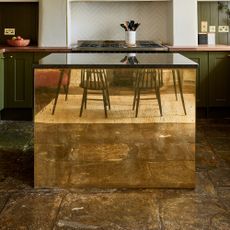 a brass fronted kitchen island reflecting a dining table and chairs