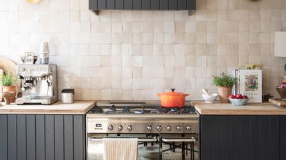 black kitchen cabinets with pink tiles and hob