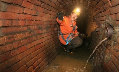 An operator crouches in a San Francisco sewer