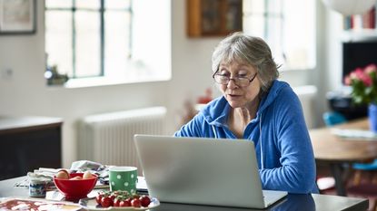A retired woman looks at her laptop as she plans her 2023 financial strategies.