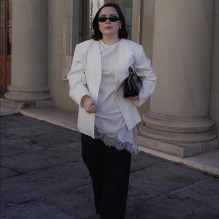 Influencer Indira C wearing a white blazer, white lace-hem cami and black trousers. 