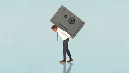 Businessman carrying heavy vault on back against blue background