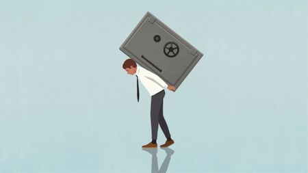 Businessman carrying heavy vault on back against blue background 
