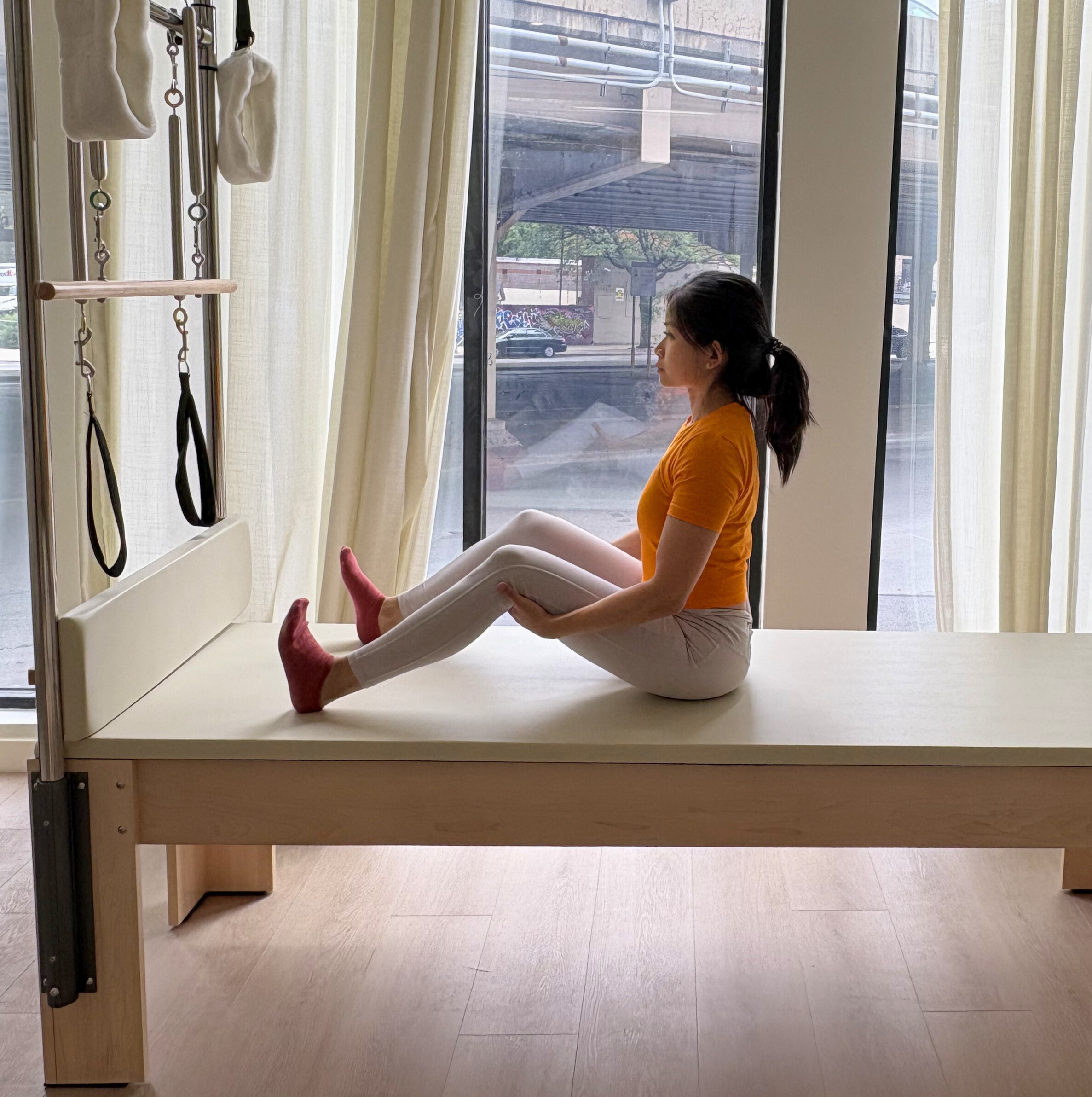 Woman demonstrates exercise on reformer bed