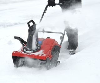 Person using a snow blower after a snow storm