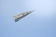 paper airplane made of US dollar bills flying in a blue sky