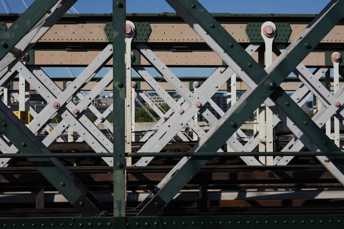 Close-up of a metal railway bridge with criss-crossing girders and rivets.