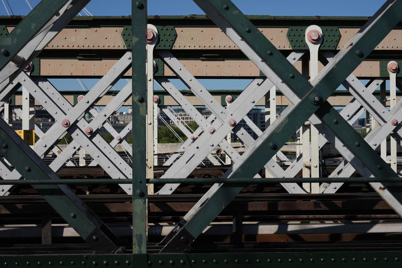 Close-up of a metal railway bridge with criss-crossing girders and rivets.