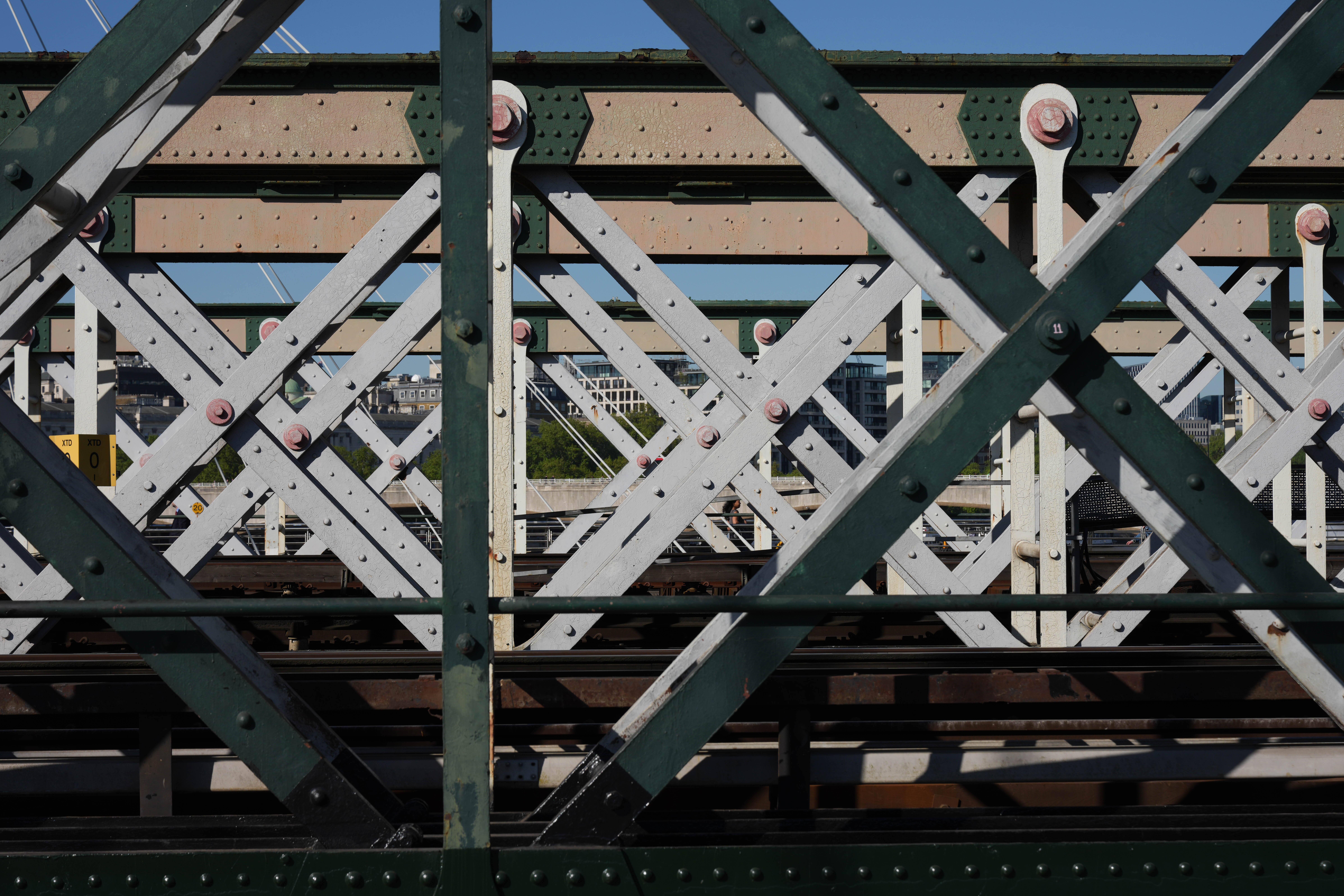 Close-up of a metal railway bridge with criss-crossing girders and rivets.