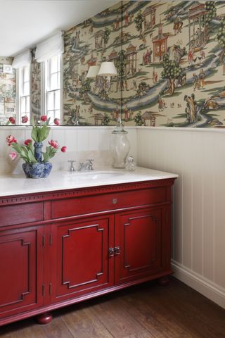 bathroom with red cabinet/vanity, dark wooden floor, chinoiserie wallpaper, mirror