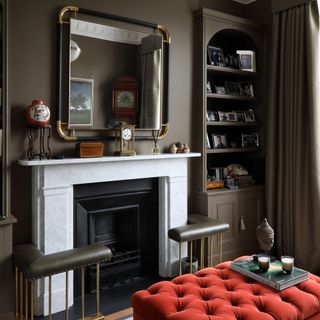 Living room with dark mushroom walls, fireplace and gold mirror.