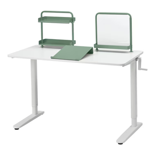 A white sit/stand desk with green accessories including an add-on organizer, a white board and a slanted writing board