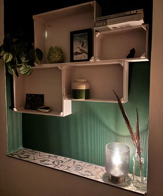 green bathroom wall with battery powered lamp and painted box shelves with house plant