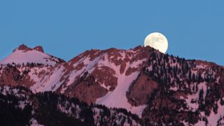 photo of moon rising over snowy mountain