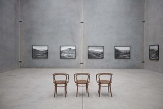 three chairs in grey room, images on opposite wall