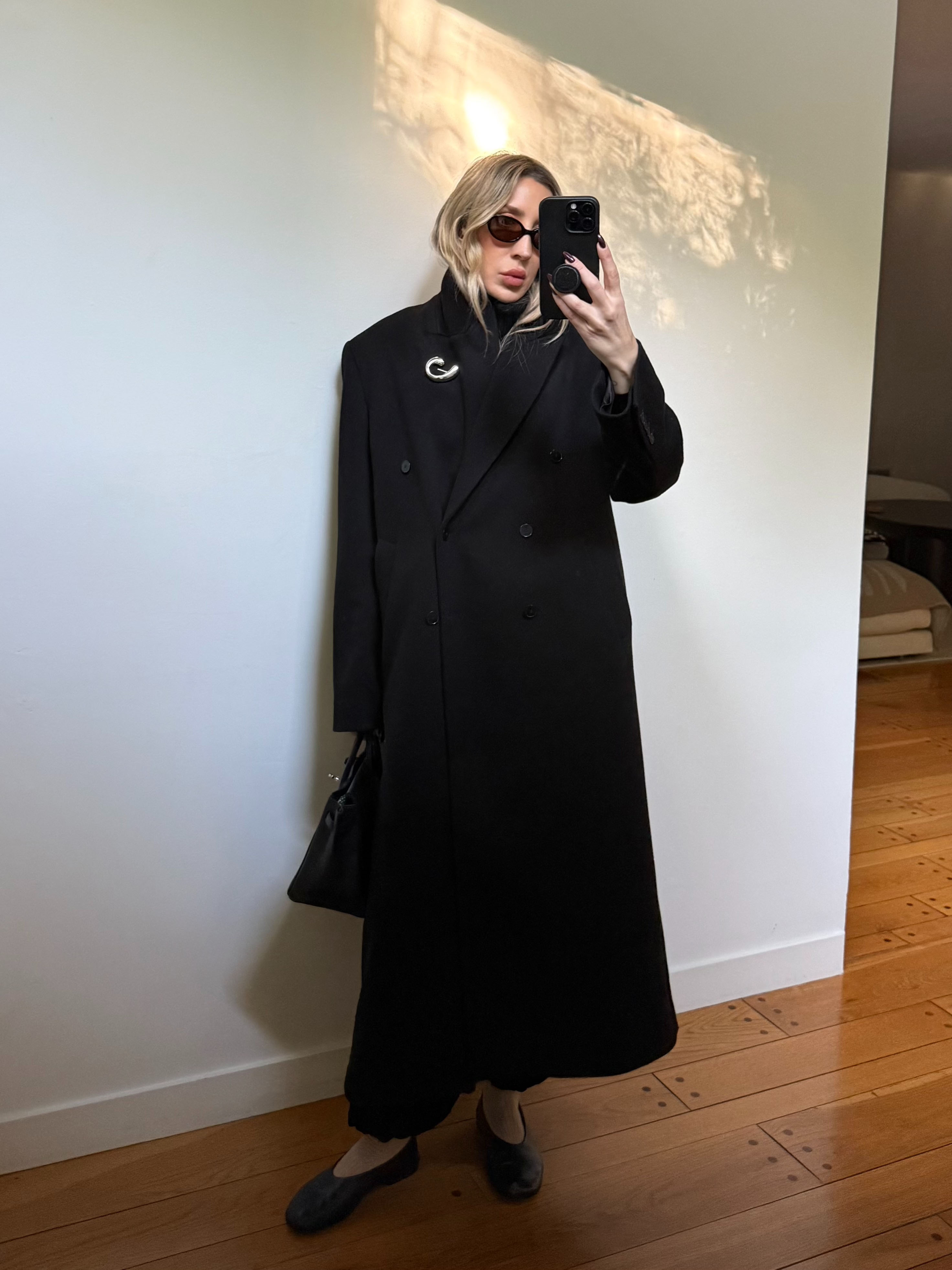 Angela Fink wearing a black coat, black pants, and flats