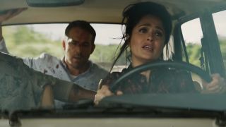 Salma Hayek driving a car with Ryan Reynolds looking scared in the backseat.