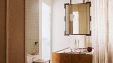 Image of a suspended mirror hanging above a burl wood sink in a mid-century-style bathroom.