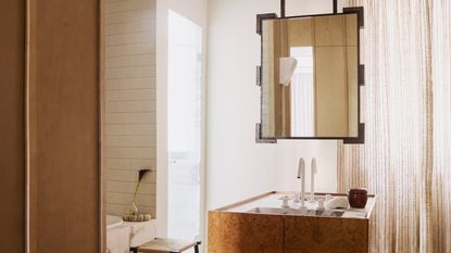 Image of a suspended mirror hanging above a burl wood sink in a mid-century-style bathroom.