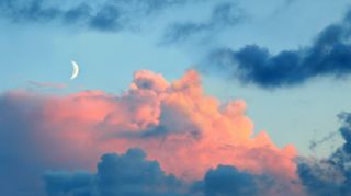 blue evening sky panorama with new moon and rose tinted clouds