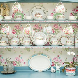 floral designed wall shelf blue counter and white designed cups and plates
