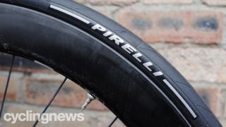 A black Pirelli tyre on a black rim against a brick wall