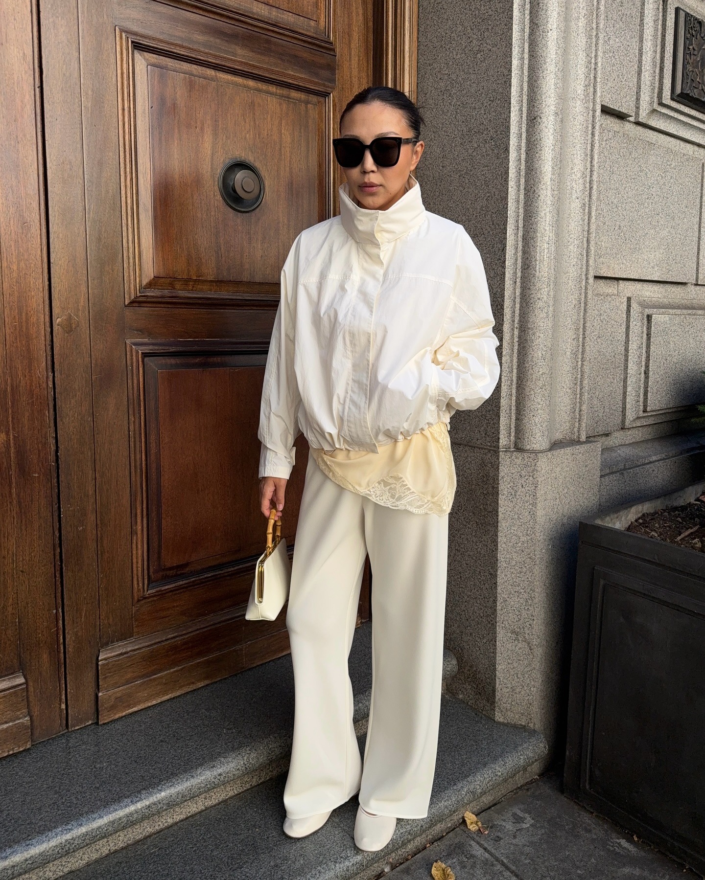 Dana Assanova wearing a white windbreaker and lace top and white pants