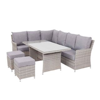 A rattan-effect outdoor corner sofa and dining table with two padded footstools