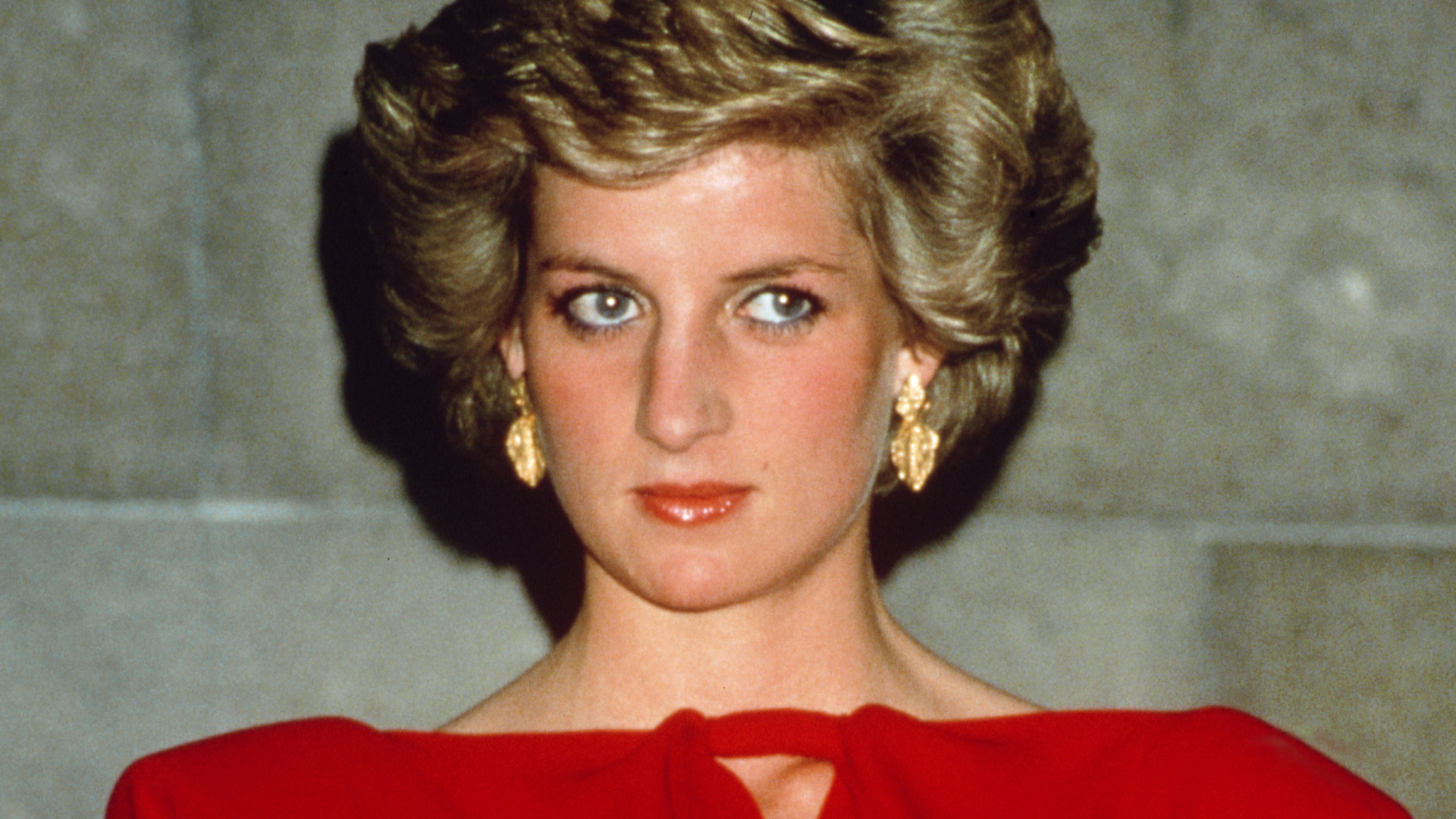 Princess Diana wearing a red off the shoulder dress and with blonde bouffant hair at a state reception in Melbourne, October 1988