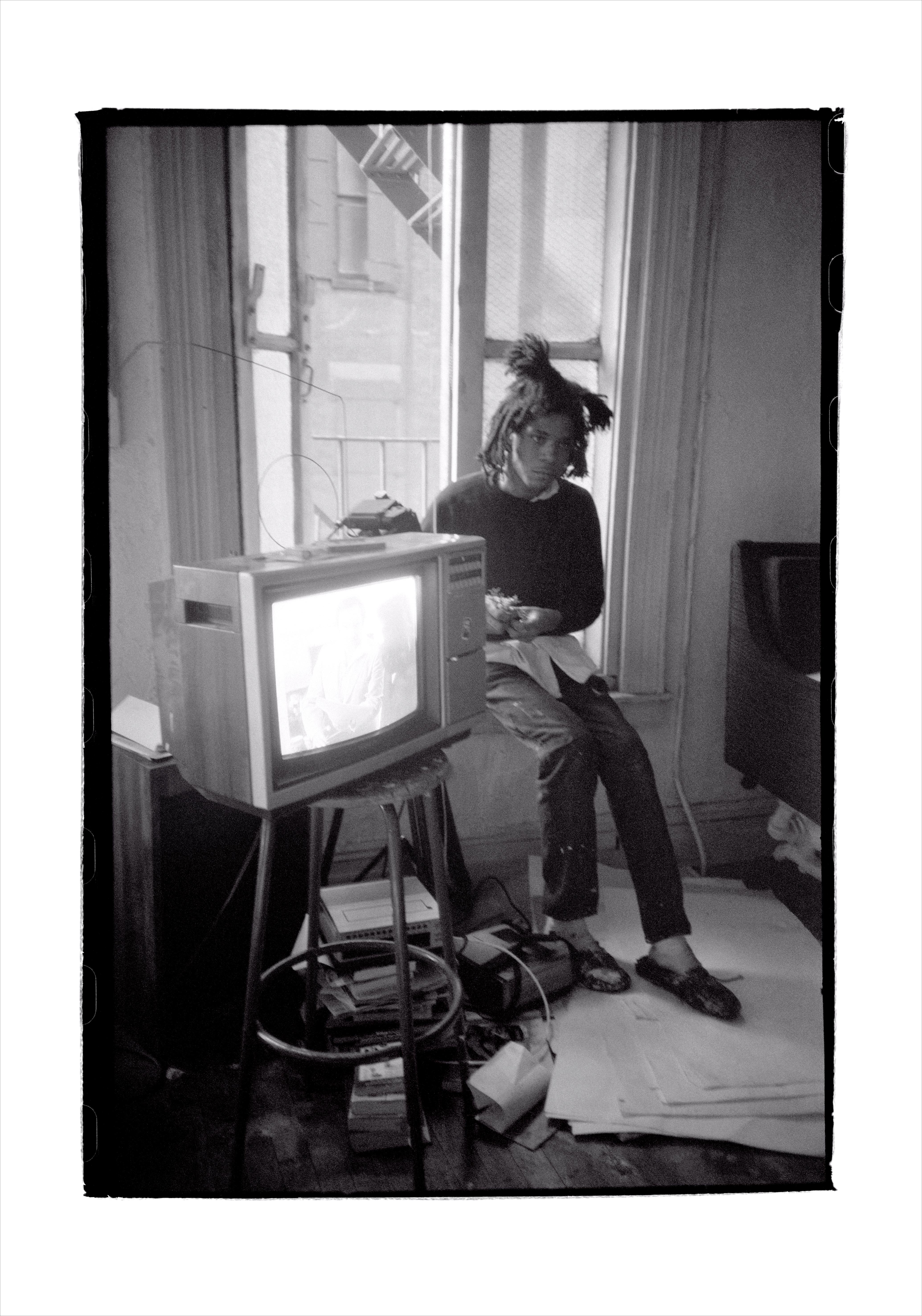 Black and white photo of Jean-Michel Basqiat beside a TV set