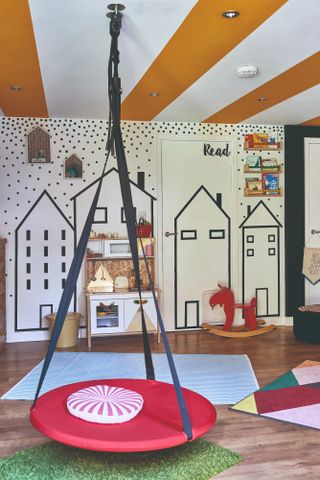 Spillett house: playroom with house wall stencils, yellow and white striped ceiling, and red and blue swing seat