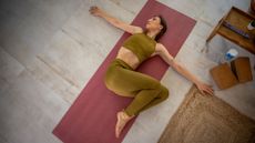 woman lies on yoga mat mid supine spinal twist
