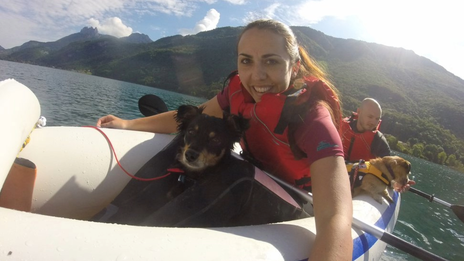 Rachel taking a selfie on a kayak with her dog, a man and another dog