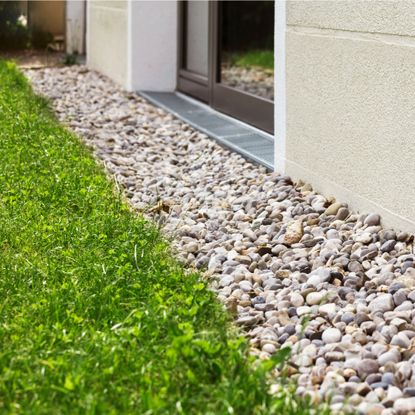 French drain with gravel running between lawn and house
