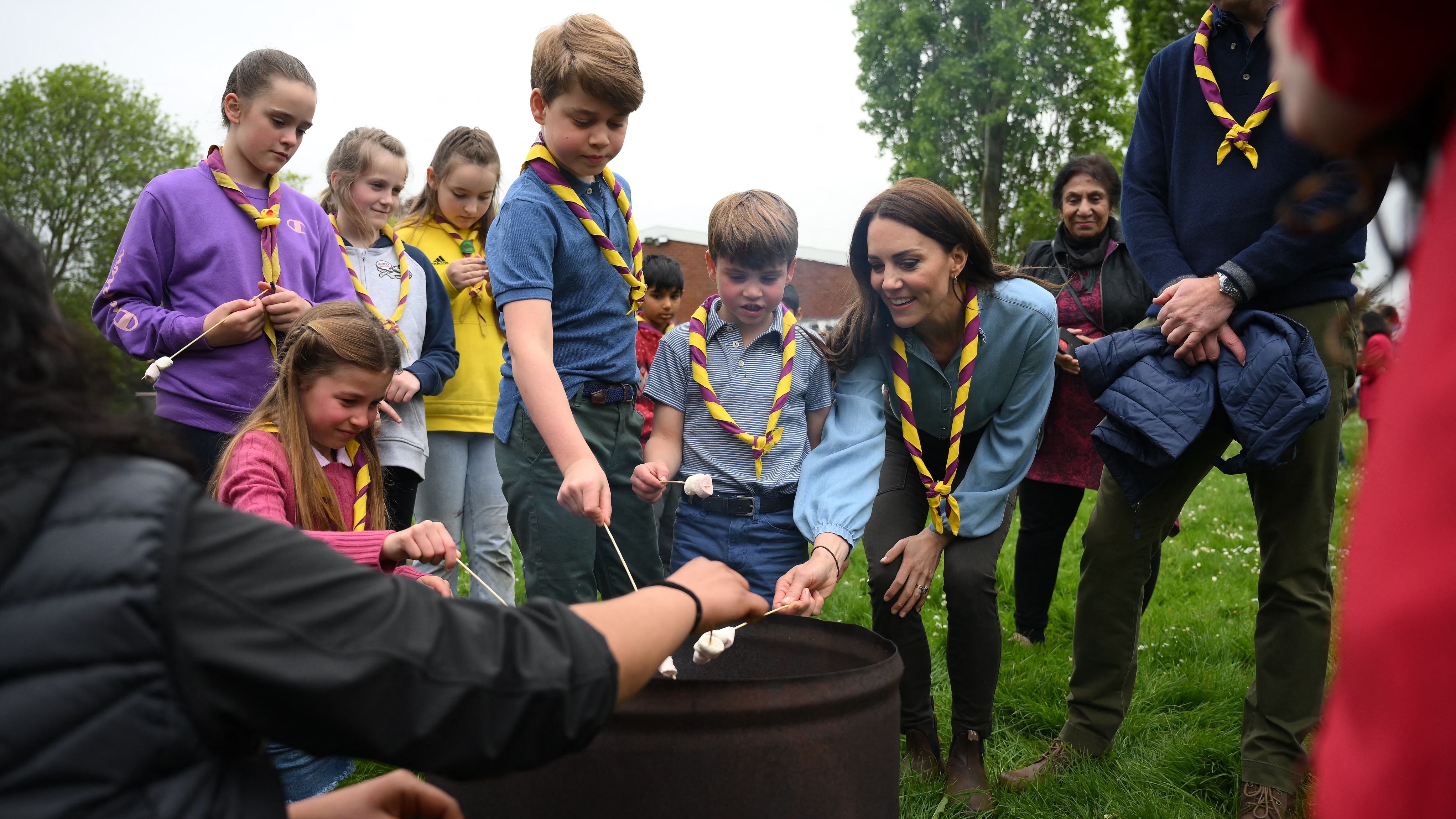 Prince William(R) looks on as (L-R) Princess Charlotte of Wales, Prince George of Wales, Prince Louis of Wales and Catherine, Princess of Wales toast marshmallows as they take part in the Big Help Out, during a visit to the 3rd Upton Scouts Hut in Slough, west of London on May 8, 202
