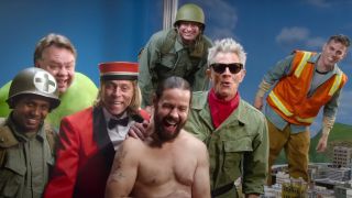 The cast of Jackass Forever stand smiling in the miniature city scene.