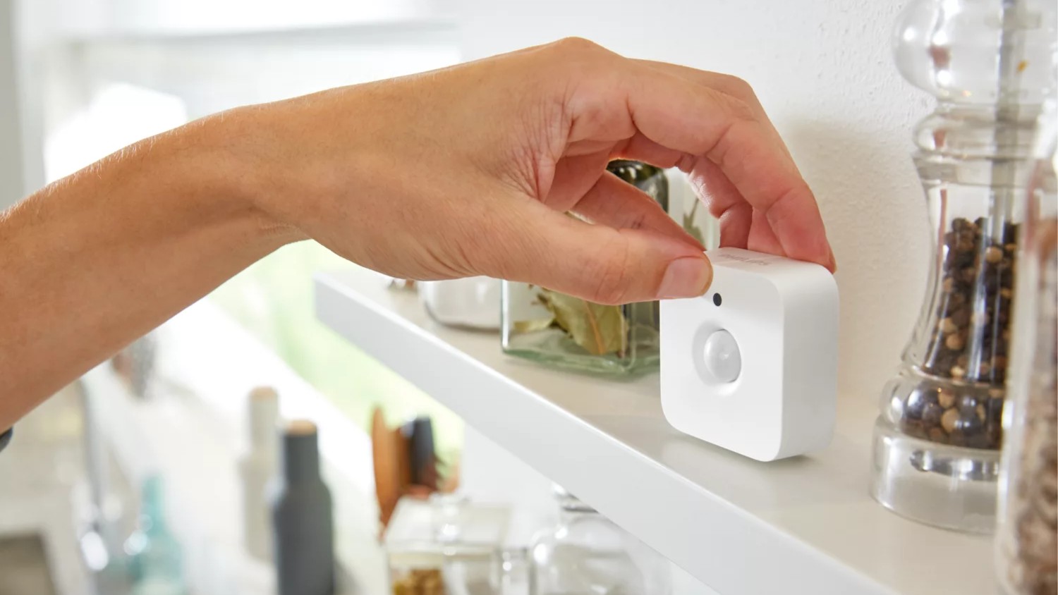 Woman's hand placing Philips Hue motion sensor on shelf