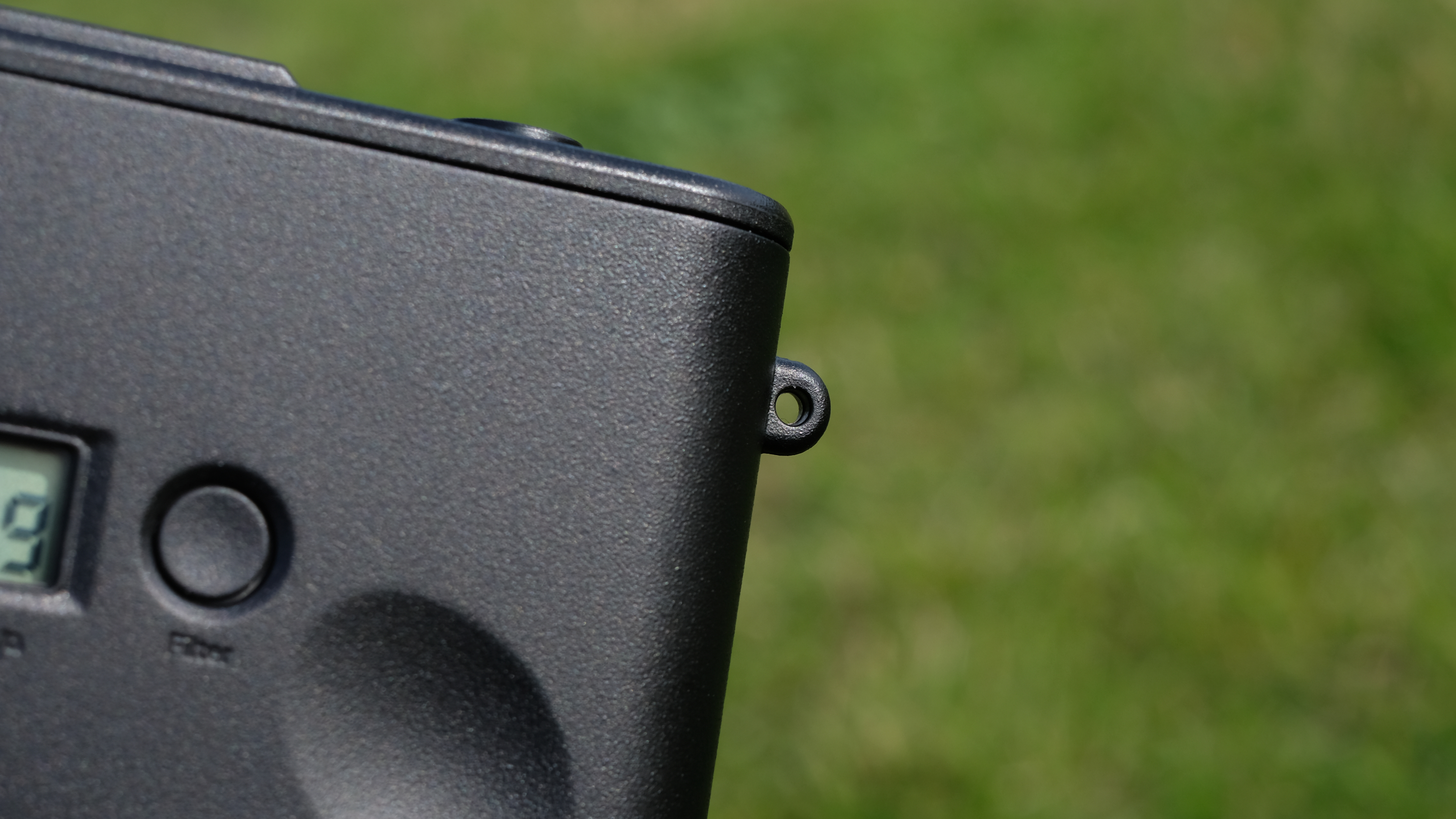 Photograph of man's hand holding Camp Snap 2 digital camera, in yellow colorway, showing close view of lug hole for strap attachment