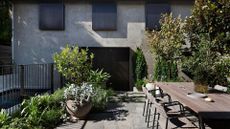 A patio with an outdoor dining space, potted plants, trees and a small pool