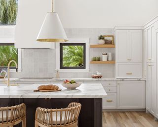 modern kitchen with white cabinets, marble kitchen island and woven bar stools