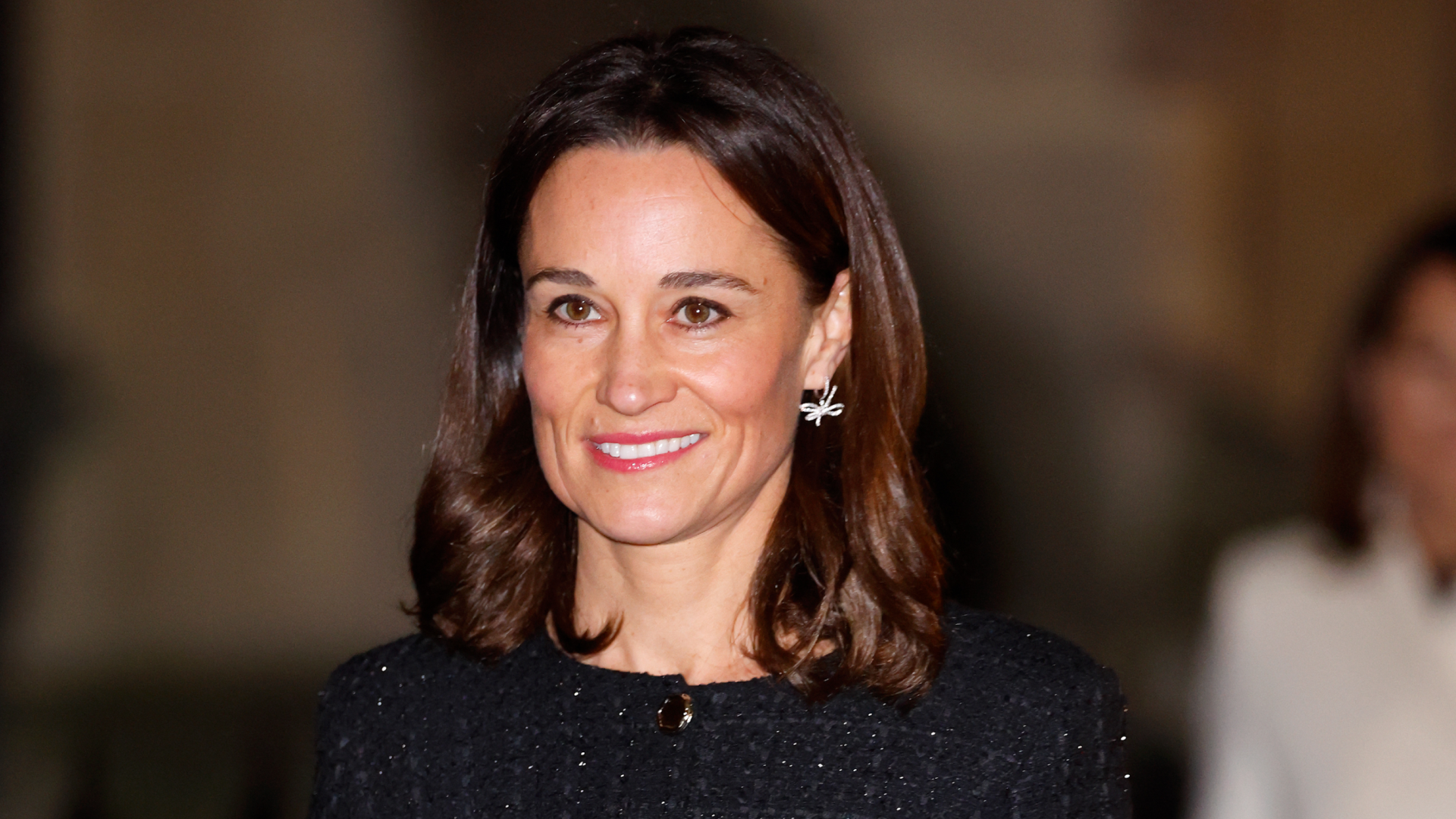 Pippa Middleton wearing a black tweed outfit and smiling