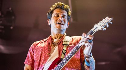 John Mayer playing an electric guitar during a stage performance